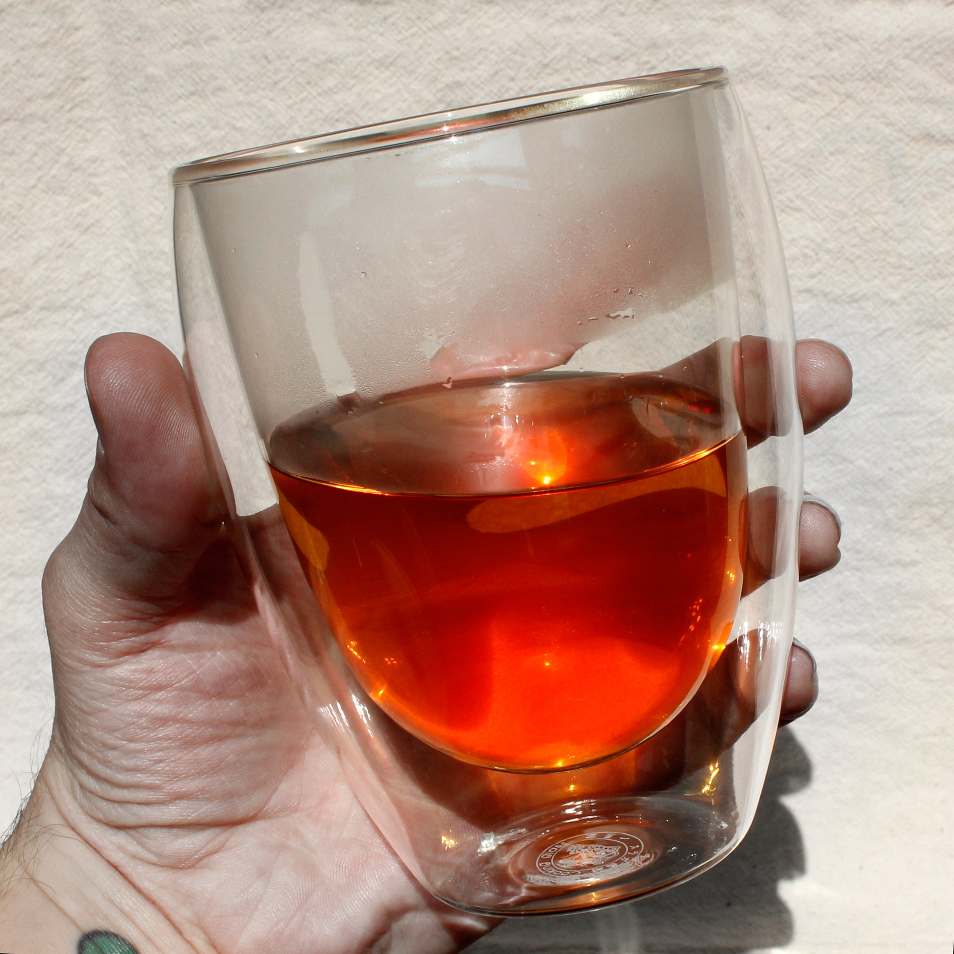Hand holding flared bubble tasting up showing how pretty the tea is inside.