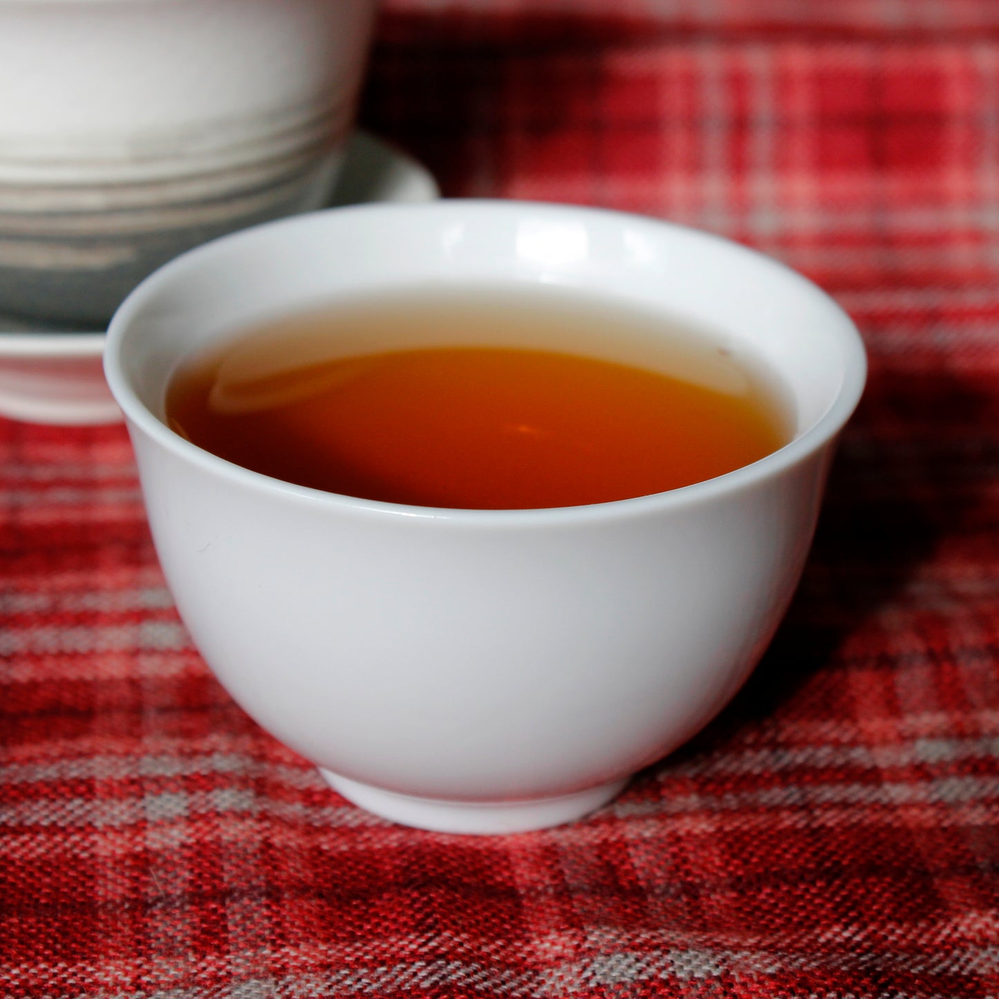 Tea in a white tea cup on a red plaid cloth. Tasting Notes:
orchid • bartlett pear • tobacco