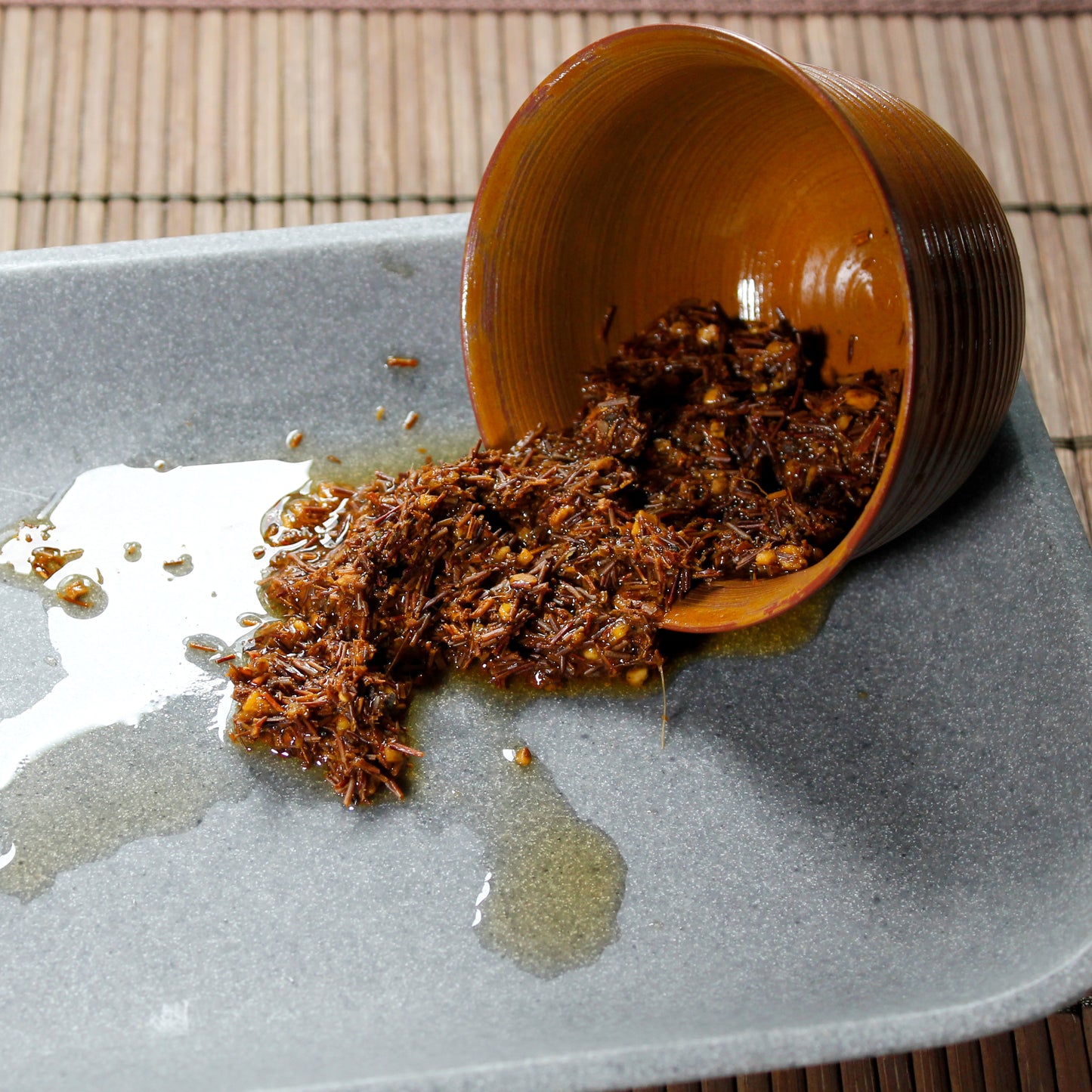 Herbal Chai - wet leaves spilling from a clay tasting cup on a stone tray on a bamboo mat. Tasting Notes:
ginger • vanilla • cinnamon