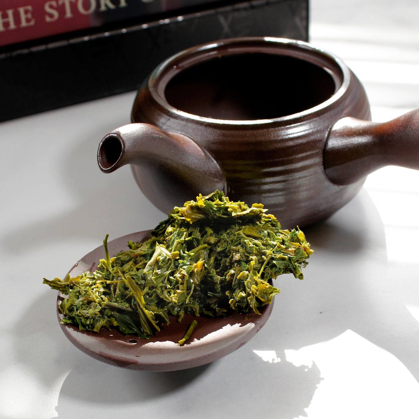 Sencha: Asamushi - wet leaves on the lid of a clay teapot with the pot in the background. Tasting Notes:
orange peel • spinach • bean sprout