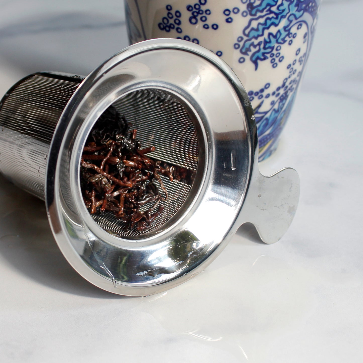 Tung Ting Hojicha - wet leaves in a stainless steel strainer. a printed mug next to it. Tasting Notes:
vanilla • dried apricot • buckwheat