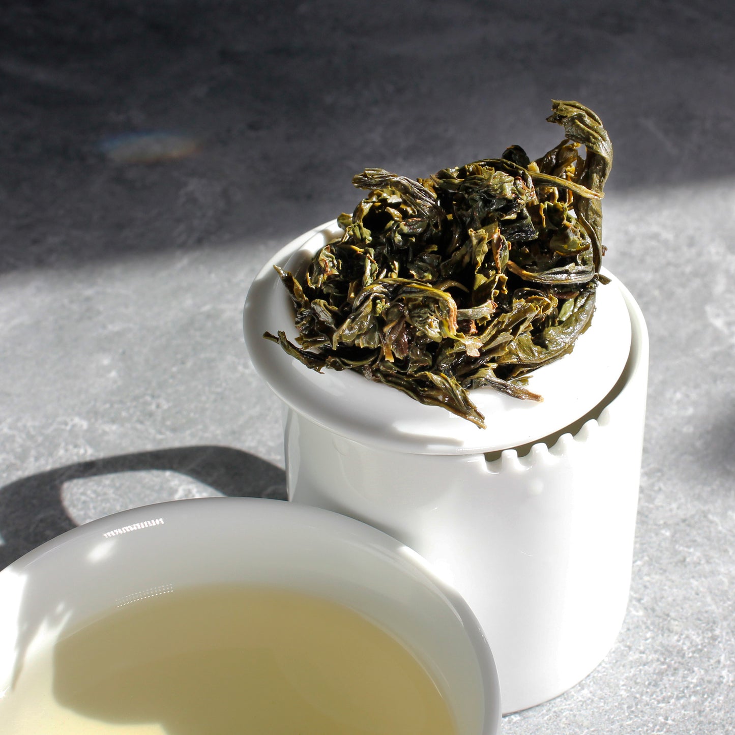 Wen Shan Bao Zhong - wet leaves on a white lid on top of a round pitcher with tea cup in foreground. Tasting Notes:
candied violet • star fruit • toast