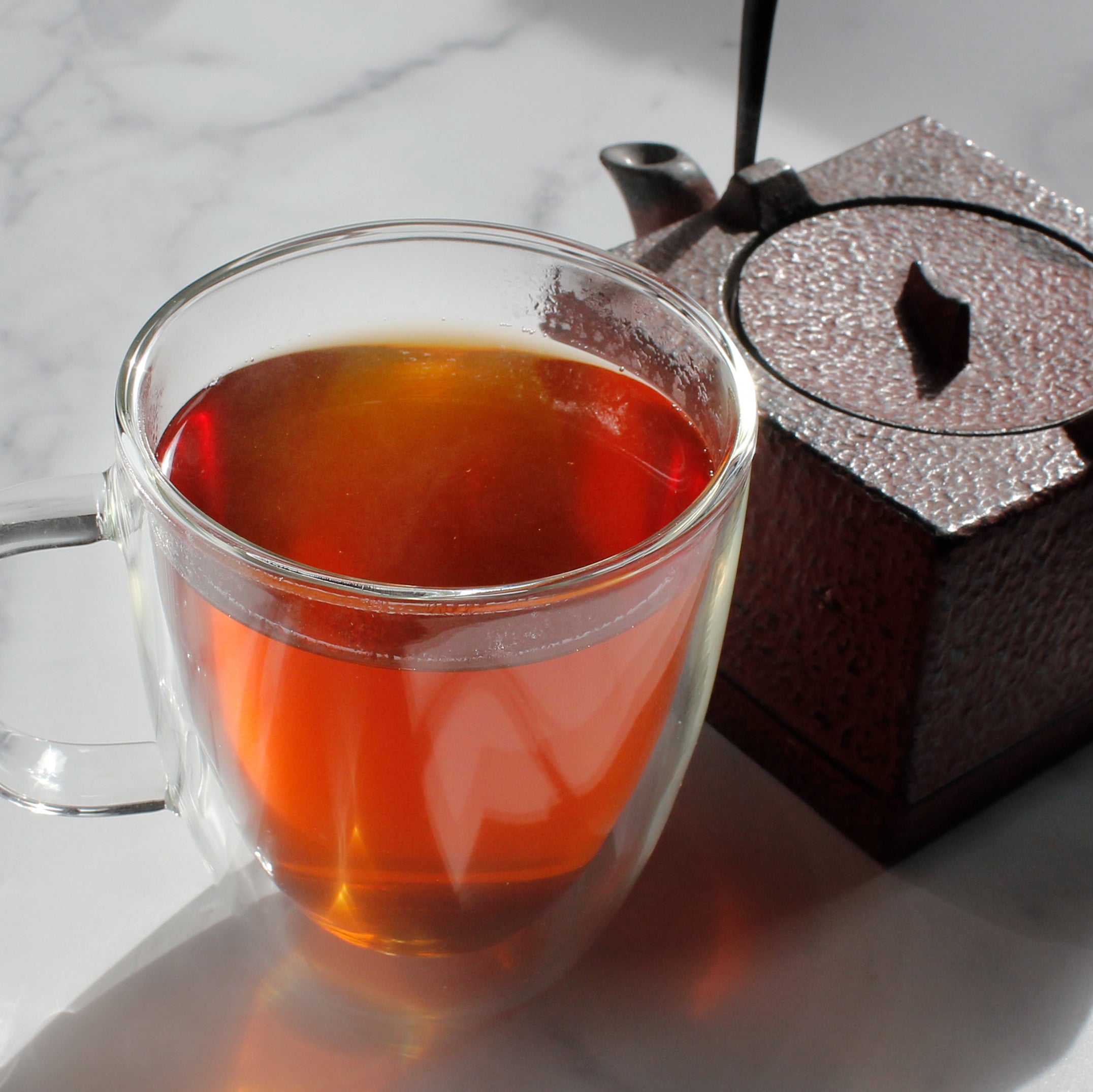 Cocoa Mint - infusion in a glass mug with a square tea pot in background. Tasting Notes:
peppermint • vanilla • milk chocolate