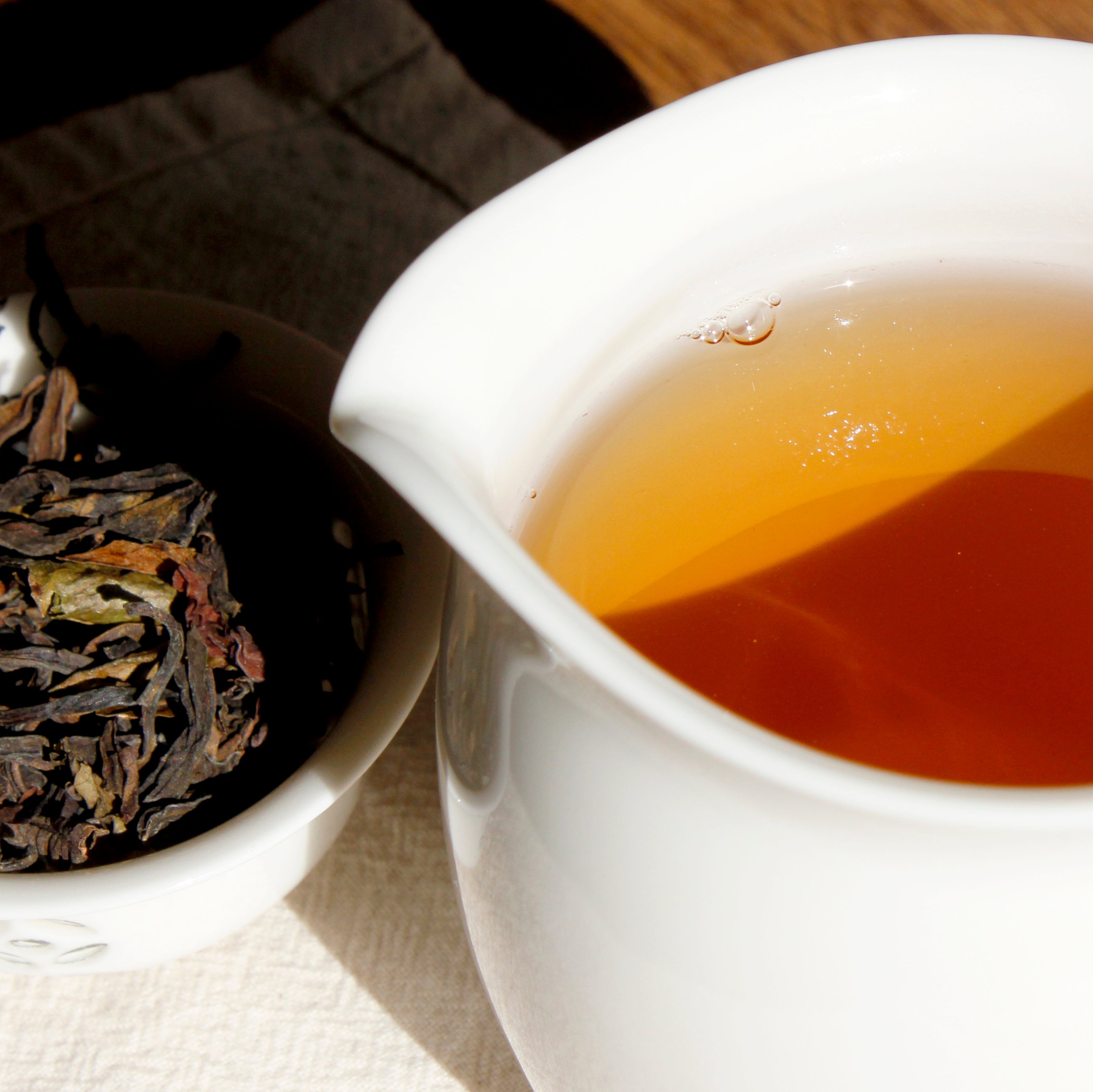 Close up of pitcher full of tea with a tea cup filled with dried tea leaves. 