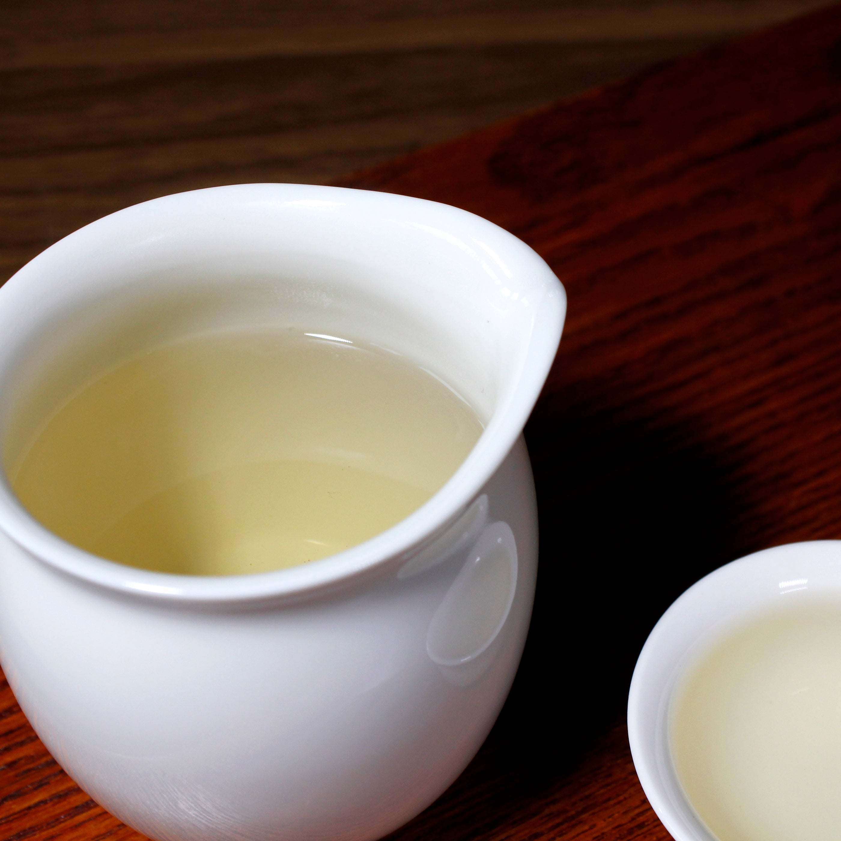White porcelain pitcher with tea and a tea cup. 