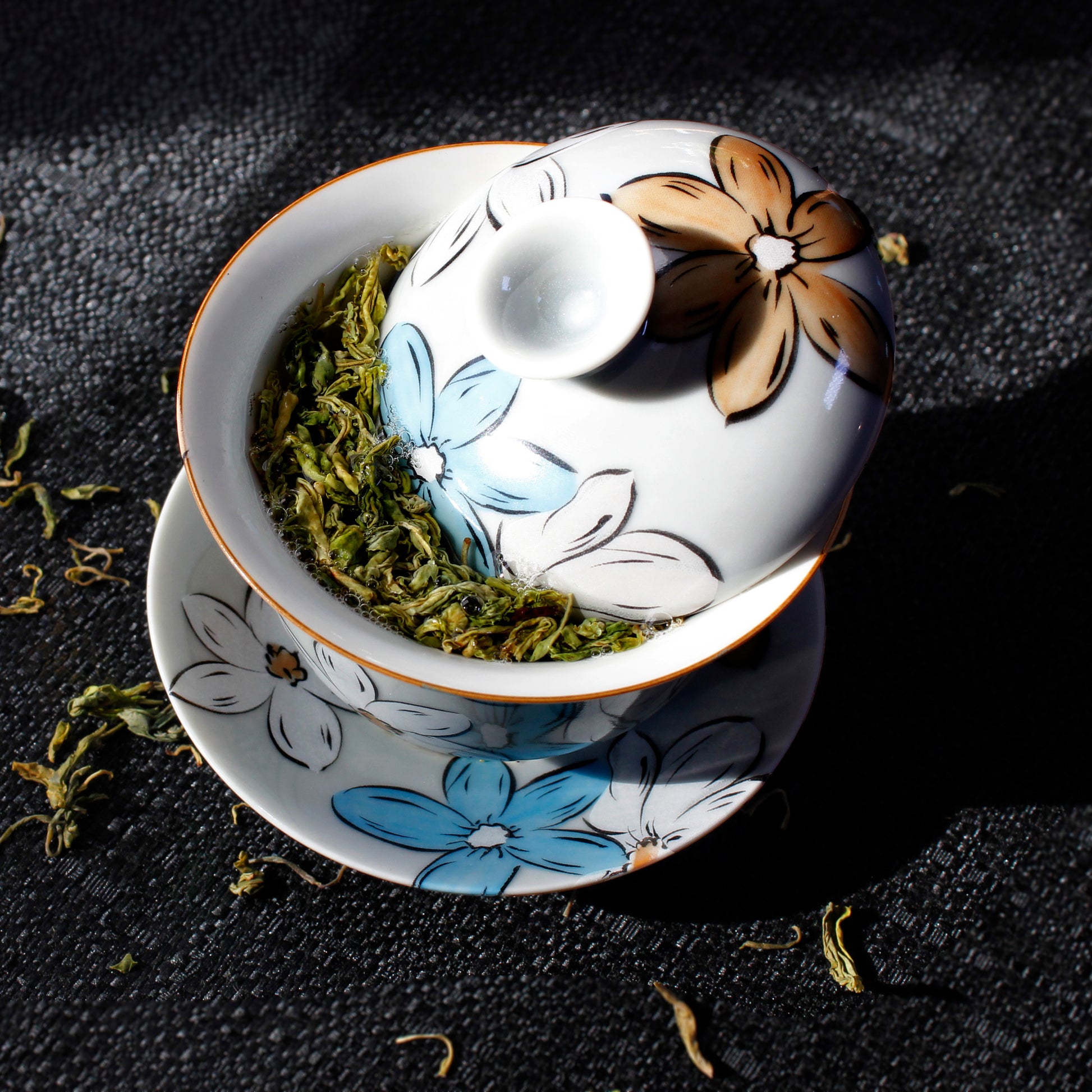 Ceramic gaiwan with floral design on a dark surface