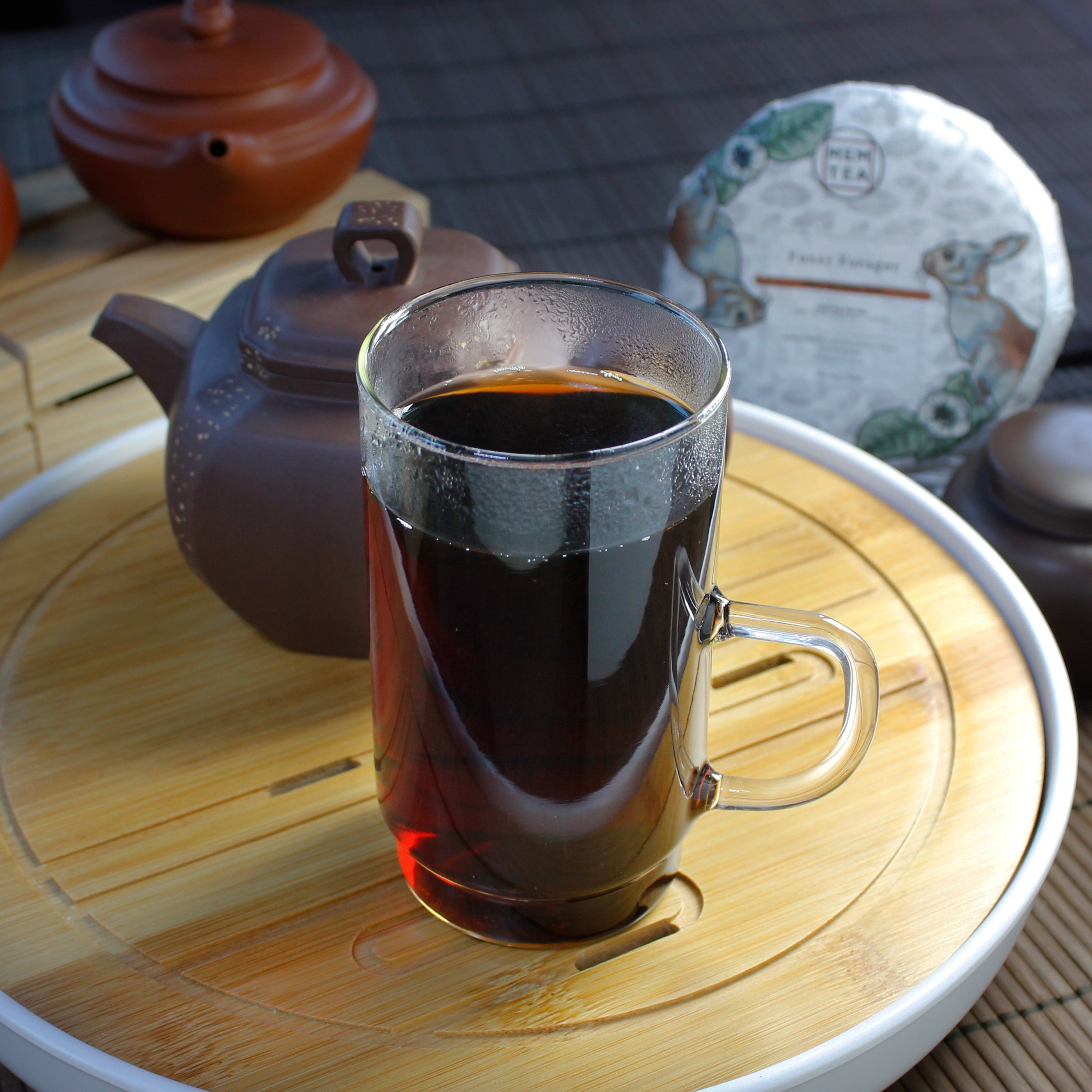 Fuzzy Forager: Shu Pu-Erh Bingcha - infusion in a tall glass mug, brown tea ware and wrapped Pu-erh in background. Tasting Notes:
peat • dried mushrooms • camphor