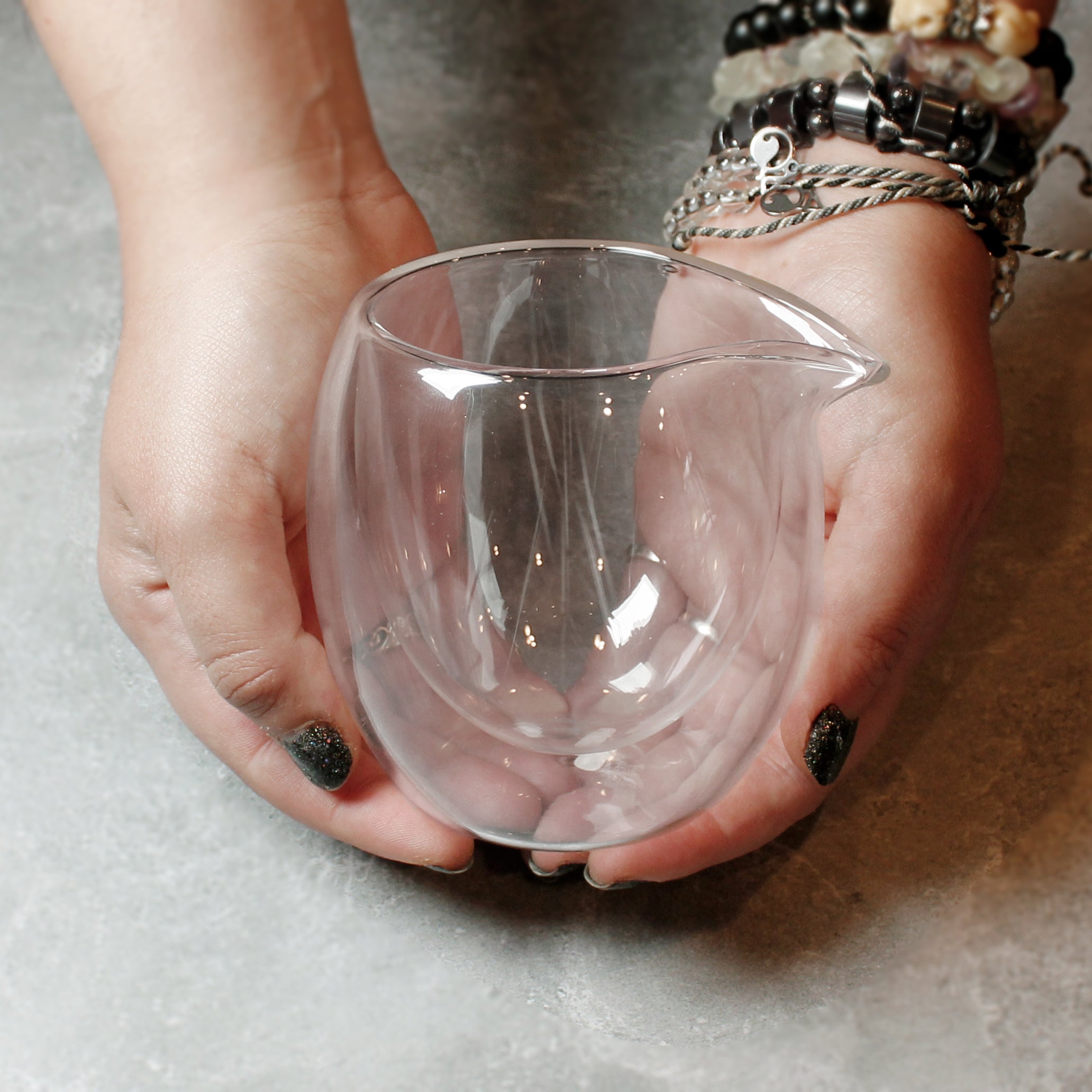 Two hands cupping the Glass Bubble sharing Pitcher to show how large it is in the hands. 