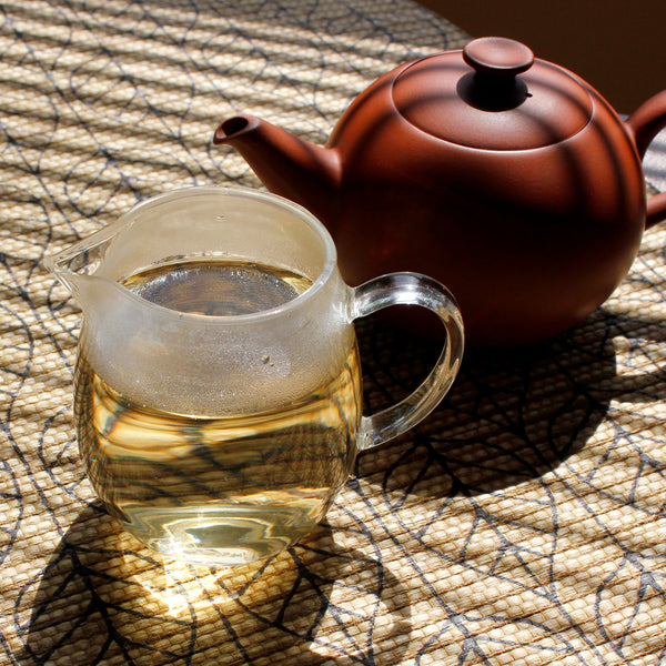 A sharing pitcher of sunkissed Moonlight White tea sits in fron of a clay teapot.