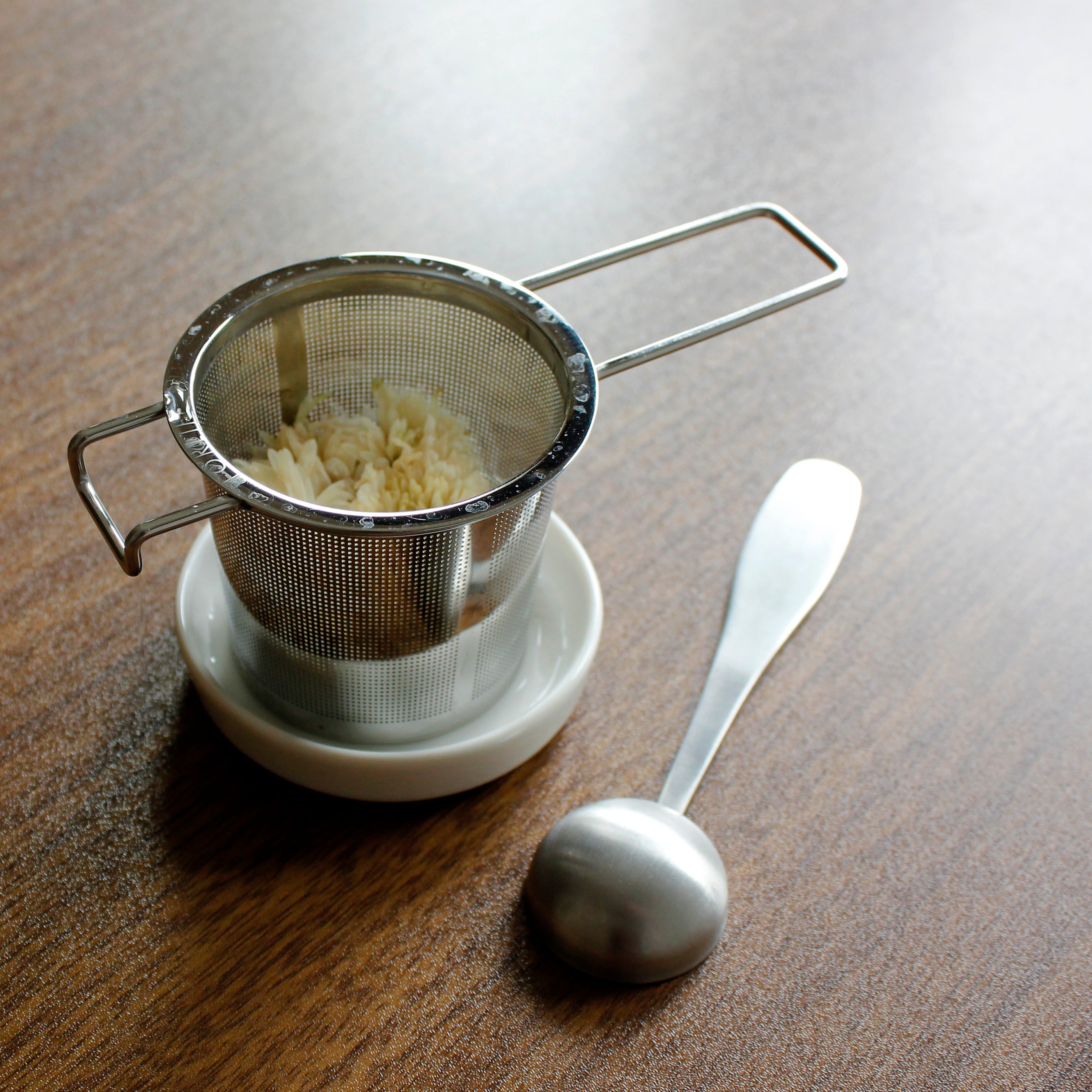 Strainer on a resting dish with tea scoop next to it. 